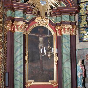 Zdjęcie nr 1: Ołtarz przyścienny, architektoniczny, z mensą w formie sarkofagu, dwustrefową, o wklęsło-wypukłych bokach. Mensa z kamiennym portatylem. Retabulum jednoosiowe, jednokondygnacyjne, ustawione na wysokim cokole, ujęte parą półfilarów kompozytowych o kanelowanych trzonach ustawionych na tle podwójnych pilastrów, z których zewnętrzne dostawione ukośnie. Podpory wspierają wyłamujące się belkowanie z architrawem wygiętym w  łuk nadwieszony nad polem środkowym i wydatnym, profilowanym gzymsem.  W zwieńczeniu przerwany, półkolisty przyczółek oraz gloria promienista z obłokami, pośrodku których aplikowany hierogram IHS. 
W polu środkowym wycięta wnęka ujęta profilowaną ramą, w kształcie stojącego prostokąta, zamkniętego łukiem nadwieszonym. We wnęce obraz z przedstawieniem  Ukrzyżowania Chrystusa, nad którym rzeźbiony kartusz formowany z ornamentu rocaille'owego.
Całość struktury ołtarza malowana w kolorze ciemnobrązowym, Półfilary, fryz oraz mensa pokryte malowaną marmoryzacją w odcieniach zieleni, pole środkowe ciemnoczerwone, detal architektoniczny  i profilowania pozłacane.