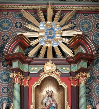 Zdjęcie nr 4: Ołtarz architektoniczny, jednoosiowy, jednokondygnacyjny ze zwieńczeniem. Ołtarz sarkofagowy, z drewnianą mensą. Retabulum na wysokim, zryzalitowany skośnie cokole, ujętym parą spływów wolutowych. Część środkowa retabulum ujęta parą kolumn ustawionych na tle zdwojonych pilastrów, wspierających wyłamujące się ponad nimi belkowanie z architrawem w kształcie odcinkowego łuku nadwieszonego na osi. Zwieńczenie w formie przerwanego, półkolistego przyczółka z motywem promienistej glorii pośrodku. Dolną i górną partię części środkowej nastawy zdobi para rocaille’owych kartuszy. Pole nastawy w formie niszy zamkniętej półkolistym łukiem nadwieszonym z uskokami, ujęte profilowaną, złoconą ramą o dłuższych bokach zdobionych motywem rocaille’ów. Wewnątrz figura Najświętszego Serca Jezusa oraz para figurek aniołków trzymających lichtarze. Dodatkowo retabulum ujmuje para figur aniołów w złoconych szatach. Pośrodku glorii zwieńczenia płaskorzeźbione tablice dekalogu ujęte wiązkami promieni i kręgiem obłoków. Struktura polichromowana w kolorze brązowym i czerwonym oraz marmoryzowana w odcieniach zieleni, detal architektoniczny i ornamentyka złocone i srebrzone. 