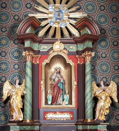 Zdjęcie nr 1: Ołtarz architektoniczny, jednoosiowy, jednokondygnacyjny ze zwieńczeniem. Ołtarz sarkofagowy, z drewnianą mensą. Retabulum na wysokim, zryzalitowany skośnie cokole, ujętym parą spływów wolutowych. Część środkowa retabulum ujęta parą kolumn ustawionych na tle zdwojonych pilastrów, wspierających wyłamujące się ponad nimi belkowanie z architrawem w kształcie odcinkowego łuku nadwieszonego na osi. Zwieńczenie w formie przerwanego, półkolistego przyczółka z motywem promienistej glorii pośrodku. Dolną i górną partię części środkowej nastawy zdobi para rocaille’owych kartuszy. Pole nastawy w formie niszy zamkniętej półkolistym łukiem nadwieszonym z uskokami, ujęte profilowaną, złoconą ramą o dłuższych bokach zdobionych motywem rocaille’ów. Wewnątrz figura Najświętszego Serca Jezusa oraz para figurek aniołków trzymających lichtarze. Dodatkowo retabulum ujmuje para figur aniołów w złoconych szatach. Pośrodku glorii zwieńczenia płaskorzeźbione tablice dekalogu ujęte wiązkami promieni i kręgiem obłoków. Struktura polichromowana w kolorze brązowym i czerwonym oraz marmoryzowana w odcieniach zieleni, detal architektoniczny i ornamentyka złocone i srebrzone. 