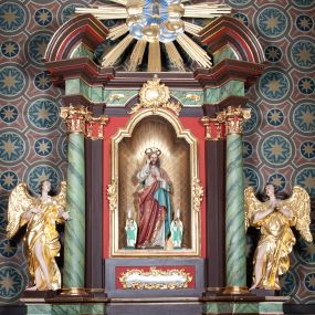 Zdjęcie nr 1: Ołtarz architektoniczny, jednoosiowy, jednokondygnacyjny ze zwieńczeniem. Ołtarz sarkofagowy, z drewnianą mensą. Retabulum na wysokim, zryzalitowany skośnie cokole, ujętym parą spływów wolutowych. Część środkowa retabulum ujęta parą kolumn ustawionych na tle zdwojonych pilastrów, wspierających wyłamujące się ponad nimi belkowanie z architrawem w kształcie odcinkowego łuku nadwieszonego na osi. Zwieńczenie w formie przerwanego, półkolistego przyczółka z motywem promienistej glorii pośrodku. Dolną i górną partię części środkowej nastawy zdobi para rocaille’owych kartuszy. Pole nastawy w formie niszy zamkniętej półkolistym łukiem nadwieszonym z uskokami, ujęte profilowaną, złoconą ramą o dłuższych bokach zdobionych motywem rocaille’ów. Wewnątrz figura Najświętszego Serca Jezusa oraz para figurek aniołków trzymających lichtarze. Dodatkowo retabulum ujmuje para figur aniołów w złoconych szatach. Pośrodku glorii zwieńczenia płaskorzeźbione tablice dekalogu ujęte wiązkami promieni i kręgiem obłoków. Struktura polichromowana w kolorze brązowym i czerwonym oraz marmoryzowana w odcieniach zieleni, detal architektoniczny i ornamentyka złocone i srebrzone. 