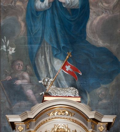 Zdjęcie nr 4: Ołtarz architektoniczny, jednoosiowy z bramkami, jednokondygnacyjny ze zwieńczeniem, na podwójnym cokole. Ołtarz murowany, licowany kamiennymi płytami, prostopadłościenny. Mensa betonowa. Antependium w formie wydłużonego, leżącego prostokąta, ujętego profilowaną ramą. Na srebrzonym polu płaskorzeźbiona, złocona dekoracja; w centrum rocaillowy kartusz ze sceną Zwiastowania Najświętszej Marii Panny, flankowany parą rocaillowych płycin, w których prawa z przedstawieniem mitry książęcej na poduszce ujętej różanymi gałązkami z gwiazdą, lewa z berłem na poduszce ujętym liliami zwieńczonej słońcem. 
Tabernaculum w formie prostopadłościennej szafki o wypukłej ścianie frontowej, z dwuskrzydłowymi drzwiczkami o kształcie zbliżonym do kwadratu, ujęte ramą; na łączeniu drzwiczek krzyż, flankowany przez odlewane kłosy zbóż i winne grono, całość na fakturowanym tle. Tabernaculum w drewnianej obudowie stanowiącej podstawę dla tronu wystawienia; cokół wyłamany, dekorowany płycinami z ornamentem roślinnym i campanullami; całość zamknięta gzymsem. Tron wystawienia w formie aediculi z obrotową niszą; ujęte parą półkolumn i parą kolumn o kapitelach kompozytowych i pseudokanelowanych trzonach dźwigających pełne belkowanie, wypukłe i wyłamane na kształt łuku odcinkowego nad niszą, wyłamane na osiach podpór. Nisza ujęta opaską dekorowaną akantem. W partii fryzu rozety i dekoracja roślinna. Całość zwieńczona postumentem  z leżącym na księdze barankiem. Tron flankują dwie figurki, adorujących aniołków, klęczących na cokole.
Nastawa ołtarzowa ujęta trzema parami pilastrów i parą skrajnych filarów o kapitelach kompozytowych i kanelowanych trzonach; oraz stojących przed nimi w dwóch strefach dwiema parami kolumn o kapitelach kompozytowych. Podpory dźwigają pełne belkowanie, wyłamane na ich osi; nad polem środkowym architraw przyjmuje kształt łuku nadwieszonego. Belkowanie oraz cokoły kolumn ustawione delikatnie pod katem względem lica retabulum. Na belkowaniu, na osi skrajnych kolumn przerwany, wolutowy przyczółek z siedzącą parą puttów. W polu środkowym  nisza w formie stojącego prostokąta zamkniętego łukiem nadwieszonym, z wklęsłymi dolnymi narożami i dolnym bokiem; ujęta profilowaną ramą; w polu płaskorzeźbiona scena z Widzeniem św. Franciszka. Zwieńczenie w formie stojącego prostokąta ujętego lizenami oraz spływami wolutowymi; zamknięte gzymsem przechodzącym w dwie zwrócone antytetycznie woluty. W polu obraz w formie stojącego owalu w profilowanej ramie z przedstawieniem św. Michała Archanioła. Retabulum ujęte bramkami z przejściami w formie stojącego prostokąta zamkniętego łukiem nadwieszonym z uskokiem, z drzwiczkami; zwieńczone podtrzymywanym przez konsolę cokołem dla figur aniołów, flankowanym spływami wolutowymi.
Cokoły dla kolumn dekorowane z trzech stron płycinami. Rama obrazu pola środkowego zdobiona na bokach rocaille z kwiatami i palmami; łuk zwieńczony rocaillowym kartuszem, flankowanym przez dwie palmy. Na gzymsie nad polem środkowym muszla. Lizeny i woluty zwieńczenia dekorowane campanullami; obraz u spodu i u góry ujęty rocaille. Na gzymsie wieńczącym dwa kwiatowe festony; na jego skraju para wazonów, całość zwieńczona stylizowanym rokokowym krzyżem.
Struktura polichromowana w kolorze kremowym, z detalami w kolorach szarym i brudnym różem; trzony kolumn marmoryzowane; ornamentyka i profile złocone.