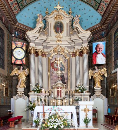 Zdjęcie nr 1: Ołtarz architektoniczny, jednoosiowy z bramkami, jednokondygnacyjny ze zwieńczeniem, na podwójnym cokole. Ołtarz murowany, licowany kamiennymi płytami, prostopadłościenny. Mensa betonowa. Antependium w formie wydłużonego, leżącego prostokąta, ujętego profilowaną ramą. Na srebrzonym polu płaskorzeźbiona, złocona dekoracja; w centrum rocaillowy kartusz ze sceną Zwiastowania Najświętszej Marii Panny, flankowany parą rocaillowych płycin, w których prawa z przedstawieniem mitry książęcej na poduszce ujętej różanymi gałązkami z gwiazdą, lewa z berłem na poduszce ujętym liliami zwieńczonej słońcem. 
Tabernaculum w formie prostopadłościennej szafki o wypukłej ścianie frontowej, z dwuskrzydłowymi drzwiczkami o kształcie zbliżonym do kwadratu, ujęte ramą; na łączeniu drzwiczek krzyż, flankowany przez odlewane kłosy zbóż i winne grono, całość na fakturowanym tle. Tabernaculum w drewnianej obudowie stanowiącej podstawę dla tronu wystawienia; cokół wyłamany, dekorowany płycinami z ornamentem roślinnym i campanullami; całość zamknięta gzymsem. Tron wystawienia w formie aediculi z obrotową niszą; ujęte parą półkolumn i parą kolumn o kapitelach kompozytowych i pseudokanelowanych trzonach dźwigających pełne belkowanie, wypukłe i wyłamane na kształt łuku odcinkowego nad niszą, wyłamane na osiach podpór. Nisza ujęta opaską dekorowaną akantem. W partii fryzu rozety i dekoracja roślinna. Całość zwieńczona postumentem  z leżącym na księdze barankiem. Tron flankują dwie figurki, adorujących aniołków, klęczących na cokole.
Nastawa ołtarzowa ujęta trzema parami pilastrów i parą skrajnych filarów o kapitelach kompozytowych i kanelowanych trzonach; oraz stojących przed nimi w dwóch strefach dwiema parami kolumn o kapitelach kompozytowych. Podpory dźwigają pełne belkowanie, wyłamane na ich osi; nad polem środkowym architraw przyjmuje kształt łuku nadwieszonego. Belkowanie oraz cokoły kolumn ustawione delikatnie pod katem względem lica retabulum. Na belkowaniu, na osi skrajnych kolumn przerwany, wolutowy przyczółek z siedzącą parą puttów. W polu środkowym  nisza w formie stojącego prostokąta zamkniętego łukiem nadwieszonym, z wklęsłymi dolnymi narożami i dolnym bokiem; ujęta profilowaną ramą; w polu płaskorzeźbiona scena z Widzeniem św. Franciszka. Zwieńczenie w formie stojącego prostokąta ujętego lizenami oraz spływami wolutowymi; zamknięte gzymsem przechodzącym w dwie zwrócone antytetycznie woluty. W polu obraz w formie stojącego owalu w profilowanej ramie z przedstawieniem św. Michała Archanioła. Retabulum ujęte bramkami z przejściami w formie stojącego prostokąta zamkniętego łukiem nadwieszonym z uskokiem, z drzwiczkami; zwieńczone podtrzymywanym przez konsolę cokołem dla figur aniołów, flankowanym spływami wolutowymi.
Cokoły dla kolumn dekorowane z trzech stron płycinami. Rama obrazu pola środkowego zdobiona na bokach rocaille z kwiatami i palmami; łuk zwieńczony rocaillowym kartuszem, flankowanym przez dwie palmy. Na gzymsie nad polem środkowym muszla. Lizeny i woluty zwieńczenia dekorowane campanullami; obraz u spodu i u góry ujęty rocaille. Na gzymsie wieńczącym dwa kwiatowe festony; na jego skraju para wazonów, całość zwieńczona stylizowanym rokokowym krzyżem.
Struktura polichromowana w kolorze kremowym, z detalami w kolorach szarym i brudnym różem; trzony kolumn marmoryzowane; ornamentyka i profile złocone.