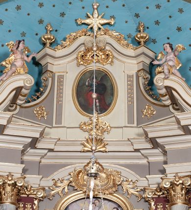 Zdjęcie nr 6: Ołtarz architektoniczny, jednoosiowy z bramkami, jednokondygnacyjny ze zwieńczeniem, na podwójnym cokole. Ołtarz murowany, licowany kamiennymi płytami, prostopadłościenny. Mensa betonowa. Antependium w formie wydłużonego, leżącego prostokąta, ujętego profilowaną ramą. Na srebrzonym polu płaskorzeźbiona, złocona dekoracja; w centrum rocaillowy kartusz ze sceną Zwiastowania Najświętszej Marii Panny, flankowany parą rocaillowych płycin, w których prawa z przedstawieniem mitry książęcej na poduszce ujętej różanymi gałązkami z gwiazdą, lewa z berłem na poduszce ujętym liliami zwieńczonej słońcem. 
Tabernaculum w formie prostopadłościennej szafki o wypukłej ścianie frontowej, z dwuskrzydłowymi drzwiczkami o kształcie zbliżonym do kwadratu, ujęte ramą; na łączeniu drzwiczek krzyż, flankowany przez odlewane kłosy zbóż i winne grono, całość na fakturowanym tle. Tabernaculum w drewnianej obudowie stanowiącej podstawę dla tronu wystawienia; cokół wyłamany, dekorowany płycinami z ornamentem roślinnym i campanullami; całość zamknięta gzymsem. Tron wystawienia w formie aediculi z obrotową niszą; ujęte parą półkolumn i parą kolumn o kapitelach kompozytowych i pseudokanelowanych trzonach dźwigających pełne belkowanie, wypukłe i wyłamane na kształt łuku odcinkowego nad niszą, wyłamane na osiach podpór. Nisza ujęta opaską dekorowaną akantem. W partii fryzu rozety i dekoracja roślinna. Całość zwieńczona postumentem  z leżącym na księdze barankiem. Tron flankują dwie figurki, adorujących aniołków, klęczących na cokole.
Nastawa ołtarzowa ujęta trzema parami pilastrów i parą skrajnych filarów o kapitelach kompozytowych i kanelowanych trzonach; oraz stojących przed nimi w dwóch strefach dwiema parami kolumn o kapitelach kompozytowych. Podpory dźwigają pełne belkowanie, wyłamane na ich osi; nad polem środkowym architraw przyjmuje kształt łuku nadwieszonego. Belkowanie oraz cokoły kolumn ustawione delikatnie pod katem względem lica retabulum. Na belkowaniu, na osi skrajnych kolumn przerwany, wolutowy przyczółek z siedzącą parą puttów. W polu środkowym  nisza w formie stojącego prostokąta zamkniętego łukiem nadwieszonym, z wklęsłymi dolnymi narożami i dolnym bokiem; ujęta profilowaną ramą; w polu płaskorzeźbiona scena z Widzeniem św. Franciszka. Zwieńczenie w formie stojącego prostokąta ujętego lizenami oraz spływami wolutowymi; zamknięte gzymsem przechodzącym w dwie zwrócone antytetycznie woluty. W polu obraz w formie stojącego owalu w profilowanej ramie z przedstawieniem św. Michała Archanioła. Retabulum ujęte bramkami z przejściami w formie stojącego prostokąta zamkniętego łukiem nadwieszonym z uskokiem, z drzwiczkami; zwieńczone podtrzymywanym przez konsolę cokołem dla figur aniołów, flankowanym spływami wolutowymi.
Cokoły dla kolumn dekorowane z trzech stron płycinami. Rama obrazu pola środkowego zdobiona na bokach rocaille z kwiatami i palmami; łuk zwieńczony rocaillowym kartuszem, flankowanym przez dwie palmy. Na gzymsie nad polem środkowym muszla. Lizeny i woluty zwieńczenia dekorowane campanullami; obraz u spodu i u góry ujęty rocaille. Na gzymsie wieńczącym dwa kwiatowe festony; na jego skraju para wazonów, całość zwieńczona stylizowanym rokokowym krzyżem.
Struktura polichromowana w kolorze kremowym, z detalami w kolorach szarym i brudnym różem; trzony kolumn marmoryzowane; ornamentyka i profile złocone.