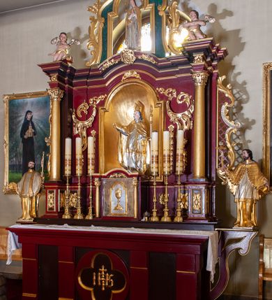 Zdjęcie nr 2: Nastawa architektoniczna, jednoosiowa, jednokondygnacyjna ze zwieńczeniem, ustawiona na cokole z wyodrębnionymi prostopadłościanami. Ołtarz drewniany, prostopadłościenny, z drewnianą mensą. Antepedium podzielone dwiema parami lizen, w centrum medalion z płyciną w formie czteroliścia, z monogramem IHS. Cokół retabulum dekorowany rozetami. Nastawa flankowana dwiema parami pilastrów i stojącą przed nimi parą kolumn o kapitelach kompozytowych, dźwigających pełne belkowanie wyłamane na ich osi, nad polem środkowym przyjmujące kształt łuku odcinkowego. Belkowanie dekorowane rozetami oraz anthemionami, nad polem środkowym małżowinowy kartusz z koroną, krzyżem i kotwicą. Na belkowaniu fragmenty przerwanego, falistego przyczółka z siedzącymi puttami. W polu środkowym nisza w formie stojącego prostokąta zamkniętego łukiem półkolistym nadwieszonym, ujęta profilowaną ramą, z figurą św. Stanisława. Nisza flankowana ornamentem małżowinowo-chrząstkowym i akantem. Kondygnacja flankowana uszami utworzonymi z akantu, karbowanej wstęgi i kratki regencyjnej. Po bokach nastawy przymocowane wsporniki z figurami św. Jana Kantego i św. Jana Nepomucena. Zwieńczenie w formie zbliżonej do prostokąta, o krawędzi kształtowanej przez woluty, dekorowanej stylizowanym ornamentem roślinnym i rokokowym. W polu prześwit w kształcie stojącego prostokąta zamkniętego łukiem półkolistym nadwieszonym, ujętym profilowaną ramą, z figurą Matki Boskiej Niepokalanie Poczętej. 
Struktura polichromowana w kolorze ciemnoczerwonym, ze złoconymi kolumnami, profilami i ornamentyką oraz srebrzonymi detalami. 

