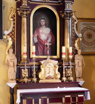 Zdjęcie nr 2: Nastawa architektoniczna, jednoosiowa, jednokondygnacyjna ze zwieńczeniem, ustawiona na cokole z wyodrębnionymi prostopadłościanami. Ołtarz drewniany, prostopadłościenny, z drewnianą mensą. Antepedium flankowane dwiema parami lizen, w centrum przedstawienie złotego krzyża na srebrzonym tle. Cokół dekorowany rozetami i akantem. Nastawa flankowana dwiema kolumnami o kapitelach kompozytowych, dźwigających pełne belkowanie wyłamane na ich osi oraz częściowo przerwane nad polem środkowym, z rozetami w partii fryzu oraz fragmenty przerwanego, wolutowego przyczółka. W polu głównym wnęka w formie stojącego prostokąta zamkniętego łukiem półkolistym, ujęta profilowaną ramą, z obrazem Najświętszego Serca Jezusa. Nad obrazem gołębica Ducha Świętego w glorii promienistej. Kondygnacja ujęta uszami utworzonymi z akantu, kratki regencyjnej i karbowanej wstęgi. Zwieńczenie w formie zbliżonej do trapezu, zamkniętego dwiema stykającymi się wolutami, ujętego spływami wolutowymi, całość obwiedziona karbowaną wstęgą. Całe pole wypełnia obraz z przedstawieniem św. Wojciecha. 
Struktura polichromowana w kolorze ciemnoczerwonym, ze złoconymi kolumnami, profilami i ornamentyką oraz srebrzonym polem zwieńczenia i detalami. 