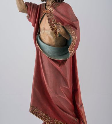 Zdjęcie nr 5: Rzeźba pełna na cokole. Chrystus ustawiony frontalnie, w kontrapoście, z ugiętą i cofniętą lewą nogą. Lewa ręka wyciągnięta do przodu prawdopodobnie przytrzymywała chorągiew, prawa jest uniesiona w górę w geście błogosławieństwa. Twarz pociągła, szczupła, o szerokim czole, głęboko osadzonych oczach, z brodą dzielącą się w dwa pukle. Włosy długie, z przedziałkiem na środku głowy, opadają na ramiona i plecy. Chrystus ubrany w podbity błękitem czerwony płaszcz ze złoconą lamówką, zapięty na piersi fibulą, przerzucony przez ramiona i zawinięty wokół lewego biodra, spięty na prawym. Ciało o wyraźnym modelunku z zaznaczonymi śladami męki. Polichromia w partiach ciała naturalistyczna. Z tyłu, na płaszczu tabliczka z napisem „Ferdinand Stuflesser / BILDHAUER / ST. ULRICH. / GRÖDEN TIROL”.