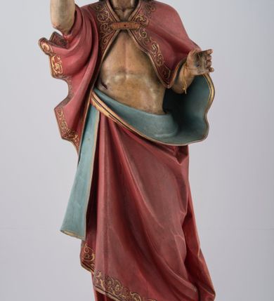 Zdjęcie nr 1: Rzeźba pełna na cokole. Chrystus ustawiony frontalnie, w kontrapoście, z ugiętą i cofniętą lewą nogą. Lewa ręka wyciągnięta do przodu prawdopodobnie przytrzymywała chorągiew, prawa jest uniesiona w górę w geście błogosławieństwa. Twarz pociągła, szczupła, o szerokim czole, głęboko osadzonych oczach, z brodą dzielącą się w dwa pukle. Włosy długie, z przedziałkiem na środku głowy, opadają na ramiona i plecy. Chrystus ubrany w podbity błękitem czerwony płaszcz ze złoconą lamówką, zapięty na piersi fibulą, przerzucony przez ramiona i zawinięty wokół lewego biodra, spięty na prawym. Ciało o wyraźnym modelunku z zaznaczonymi śladami męki. Polichromia w partiach ciała naturalistyczna. Z tyłu, na płaszczu tabliczka z napisem „Ferdinand Stuflesser / BILDHAUER / ST. ULRICH. / GRÖDEN TIROL”.