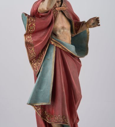 Zdjęcie nr 4: Rzeźba pełna na cokole. Chrystus ustawiony frontalnie, w kontrapoście, z ugiętą i cofniętą lewą nogą. Lewa ręka wyciągnięta do przodu prawdopodobnie przytrzymywała chorągiew, prawa jest uniesiona w górę w geście błogosławieństwa. Twarz pociągła, szczupła, o szerokim czole, głęboko osadzonych oczach, z brodą dzielącą się w dwa pukle. Włosy długie, z przedziałkiem na środku głowy, opadają na ramiona i plecy. Chrystus ubrany w podbity błękitem czerwony płaszcz ze złoconą lamówką, zapięty na piersi fibulą, przerzucony przez ramiona i zawinięty wokół lewego biodra, spięty na prawym. Ciało o wyraźnym modelunku z zaznaczonymi śladami męki. Polichromia w partiach ciała naturalistyczna. Z tyłu, na płaszczu tabliczka z napisem „Ferdinand Stuflesser / BILDHAUER / ST. ULRICH. / GRÖDEN TIROL”.