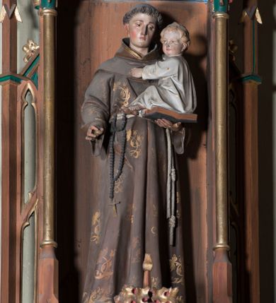 Zdjęcie nr 1: Rzeźba pełna przedstawiająca stojącego frontalnie św. Antoniego Padewskiego z Dzieciątkiem Jezus. Święty ukazany w lekkim kontrapoście, z głową skierowaną w lewo, lekko pochyloną. Oczy ma opuszczone, nos prosty, usta wąskie; na głowie tonsurę, włosy ciemne. Święty jest ubrany w brązowy habit franciszkański dekorowany złotymi motywami kwiatowymi, przepasany sznurem z różańcem. Prawą rękę ma opuszczoną, lekko wyciągniętą do przodu w subtelnym geście, lewą podtrzymuje otwartą księgę, na której siedzi Dzieciątko Jezus z jasnymi włosami, odziane w białą suknię. 
Polichromia w partiach ciała naturalistyczna.
