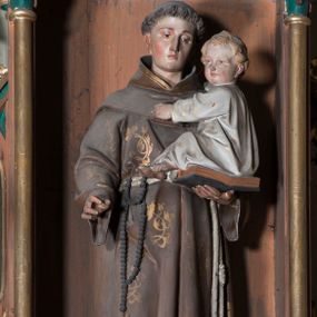 Zdjęcie nr 1: Rzeźba pełna przedstawiająca stojącego frontalnie św. Antoniego Padewskiego z Dzieciątkiem Jezus. Święty ukazany w lekkim kontrapoście, z głową skierowaną w lewo, lekko pochyloną. Oczy ma opuszczone, nos prosty, usta wąskie; na głowie tonsurę, włosy ciemne. Święty jest ubrany w brązowy habit franciszkański dekorowany złotymi motywami kwiatowymi, przepasany sznurem z różańcem. Prawą rękę ma opuszczoną, lekko wyciągniętą do przodu w subtelnym geście, lewą podtrzymuje otwartą księgę, na której siedzi Dzieciątko Jezus z jasnymi włosami, odziane w białą suknię. 
Polichromia w partiach ciała naturalistyczna.
