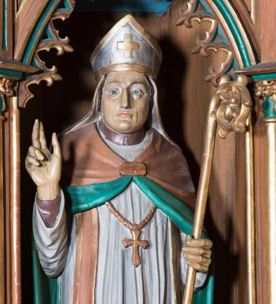 Zdjęcie nr 1: Rzeźba pełna na cokole przedstawiająca św. Stanisława stojącego frontalnie. Święty ma głowę zwróconą nieznacznie w prawo, wzrok skierowany przed siebie, nos prosty, usta wąskie;  na głowie ma infułę. Prawą rękę unosi w geście błogosławieństwa, lewą podtrzymuje złocony pastorał. Święty jest ubrany w brązową albę, białą komżę ze złoconą koronką u dołu, jasnobrązową stułę, ze złoconymi brzegami, złoty krzyż biskupi i jasnobrązowy płaszcz z zielonym podszyciem, spięty fibulą na piersi. Spod szat widoczne brązowe buty. 
Polichromia w partiach ciała naturalistyczna.
