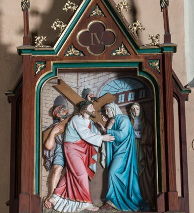 Zdjęcie nr 4: Stacje drogi krzyżowej wkomponowane w rozbudowane, drewniane neogotyckie ramy o formach przypominających kapliczki, flankowane uszakami w kształcie przypór oraz zwieńczone parami pinakli i wimpergą dekorowaną żabkami i zakończoną kwiatonem z krzyżem. Wpisano w nie motyw czworoliścia otoczony trzema rozetkami. Od dołu dekoracyjne podwieszenie. Poszczególne przedstawienia umieszczone za szybą, ujętą w profilowane obramienie w kształcie stojącego prostokąta zamkniętego łukiem nadwieszonym. Sceny są płaskorzeźbione w głębokim reliefie i ukazane na malowanym tle. Dominują zwarte, wielopostaciowe kompozycje o ekspresji wyrażonej zarówno w gestach postaci, jak i mimice twarzy. Kolorystyka pastelowa, dominują odcienie brązu, bieli i niebieskiego ożywione akcentami intensywnej czerwieni płaszcza Chrystusa. W tle fragmenty zabudowań oraz niebo, przybierające barwę od jasnego błękitu po intensywnie niebieski. W czworoliściu wimpergi numery stacji wyrażone cyframi rzymskimi, w dolnej partii obramienia prostokątne płyciny z nazwami stacji:
„I : P(an) Jezus przez Piłata na śmierć skazany”,
„II: P(an) Jezus obciążony krzyżem”, „III: P(an) Jezus upada pierwszy raz”, „IV: P(an) Jezus spotyka swą Matkę”, „V: P(an) Jezusowi dopomaga Szymon Cyre”, „VI: P(an) Jezusowi ociera twarz S. Weronika”, „VII: P(an) Jezus upada drugi raz”, „VIII: P(an) Jezus pociesza płaczące niewiasty”, „IX: P(an) Jezus upada po raz trzeci”, „X: P(an) Jezus obnażony żółcią napawany”, „XI: P(an) Jezus do krzyża przybijany”, „XII: P(an) Jezus umiera na krzyżu”, „XIII: P(an) Jezus zdjęty z krzyża”
„XIV: P(an) Jezus złożony w grobie”. 
