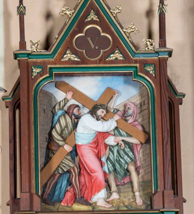 Zdjęcie nr 5: Stacje drogi krzyżowej wkomponowane w rozbudowane, drewniane neogotyckie ramy o formach przypominających kapliczki, flankowane uszakami w kształcie przypór oraz zwieńczone parami pinakli i wimpergą dekorowaną żabkami i zakończoną kwiatonem z krzyżem. Wpisano w nie motyw czworoliścia otoczony trzema rozetkami. Od dołu dekoracyjne podwieszenie. Poszczególne przedstawienia umieszczone za szybą, ujętą w profilowane obramienie w kształcie stojącego prostokąta zamkniętego łukiem nadwieszonym. Sceny są płaskorzeźbione w głębokim reliefie i ukazane na malowanym tle. Dominują zwarte, wielopostaciowe kompozycje o ekspresji wyrażonej zarówno w gestach postaci, jak i mimice twarzy. Kolorystyka pastelowa, dominują odcienie brązu, bieli i niebieskiego ożywione akcentami intensywnej czerwieni płaszcza Chrystusa. W tle fragmenty zabudowań oraz niebo, przybierające barwę od jasnego błękitu po intensywnie niebieski. W czworoliściu wimpergi numery stacji wyrażone cyframi rzymskimi, w dolnej partii obramienia prostokątne płyciny z nazwami stacji:
„I : P(an) Jezus przez Piłata na śmierć skazany”,
„II: P(an) Jezus obciążony krzyżem”, „III: P(an) Jezus upada pierwszy raz”, „IV: P(an) Jezus spotyka swą Matkę”, „V: P(an) Jezusowi dopomaga Szymon Cyre”, „VI: P(an) Jezusowi ociera twarz S. Weronika”, „VII: P(an) Jezus upada drugi raz”, „VIII: P(an) Jezus pociesza płaczące niewiasty”, „IX: P(an) Jezus upada po raz trzeci”, „X: P(an) Jezus obnażony żółcią napawany”, „XI: P(an) Jezus do krzyża przybijany”, „XII: P(an) Jezus umiera na krzyżu”, „XIII: P(an) Jezus zdjęty z krzyża”
„XIV: P(an) Jezus złożony w grobie”. 
