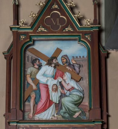 Zdjęcie nr 6: Stacje drogi krzyżowej wkomponowane w rozbudowane, drewniane neogotyckie ramy o formach przypominających kapliczki, flankowane uszakami w kształcie przypór oraz zwieńczone parami pinakli i wimpergą dekorowaną żabkami i zakończoną kwiatonem z krzyżem. Wpisano w nie motyw czworoliścia otoczony trzema rozetkami. Od dołu dekoracyjne podwieszenie. Poszczególne przedstawienia umieszczone za szybą, ujętą w profilowane obramienie w kształcie stojącego prostokąta zamkniętego łukiem nadwieszonym. Sceny są płaskorzeźbione w głębokim reliefie i ukazane na malowanym tle. Dominują zwarte, wielopostaciowe kompozycje o ekspresji wyrażonej zarówno w gestach postaci, jak i mimice twarzy. Kolorystyka pastelowa, dominują odcienie brązu, bieli i niebieskiego ożywione akcentami intensywnej czerwieni płaszcza Chrystusa. W tle fragmenty zabudowań oraz niebo, przybierające barwę od jasnego błękitu po intensywnie niebieski. W czworoliściu wimpergi numery stacji wyrażone cyframi rzymskimi, w dolnej partii obramienia prostokątne płyciny z nazwami stacji:
„I : P(an) Jezus przez Piłata na śmierć skazany”,
„II: P(an) Jezus obciążony krzyżem”, „III: P(an) Jezus upada pierwszy raz”, „IV: P(an) Jezus spotyka swą Matkę”, „V: P(an) Jezusowi dopomaga Szymon Cyre”, „VI: P(an) Jezusowi ociera twarz S. Weronika”, „VII: P(an) Jezus upada drugi raz”, „VIII: P(an) Jezus pociesza płaczące niewiasty”, „IX: P(an) Jezus upada po raz trzeci”, „X: P(an) Jezus obnażony żółcią napawany”, „XI: P(an) Jezus do krzyża przybijany”, „XII: P(an) Jezus umiera na krzyżu”, „XIII: P(an) Jezus zdjęty z krzyża”
„XIV: P(an) Jezus złożony w grobie”. 
