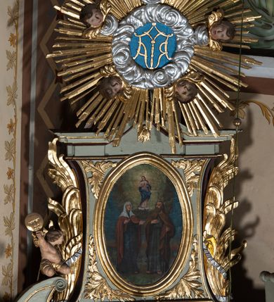 Zdjęcie nr 9: Nastawa architektoniczna, jednoosiowa, jednokondygnacyjna ze zwieńczeniem, ustawiona na cokole z wyodrębnionymi po bokach dwoma postumentami. Ołtarz prostopadłościenny z drewnianą mensą, z portatylem. Antepedium z kwiecistej tkaniny, z wyhaftowanym monogramem Marii w centrum, ujęte profilowaną ramą. Nastawa flankowana parą kolumn o skręconych trzonach i kapitelach kompozytowych stojących na tle dwóch par pilastrów o trzonach dekorowanych kampanulami. Podpory dźwigają pełne belkowanie, wyłamane na ich osi, o wklęsłym zarysie, przerwane nad polem środkowym, z fryzem dekorowanym rozetami oraz fragmenty przerwanego, falistego przyczółka ozdobionego kampanulami z parą puttów z wachlarzami. W polu nisza w formie stojącego prostokąta z obrazem Matki Boskiej Niepokalanie Poczętej w profilowanej ramie, flankowana dwiema gablotami z wotami. Nad polem środkowym dwa putta trzymające koronę zamkniętą oraz ryngraf malowany na blasze z przedstawieniem Matki Boskiej Bolesnej. Nastawa flankowana uszami utworzonymi z akantu i wstęgi regencyjnej. Zwieńczenie w formie stojącego prostokąta, o wklęsłych bokach, zamkniętego odcinkiem gzymsu wyłamanym w łuk ostry, ujęte liśćmi palmowymi z wstęgą. Całość zamknięta medalionem z monogramem Marii, w otoku z obłoków i uskrzydlonych główek anielskich, w glorii promienistej. W polu obraz przedstawiający Rodzinę Marii w formie stojącego owalu, w profilowanej ramie. Pole zwieńczenia wypełnione ornamentem roślinnym. Struktura architektoniczna polichromowana w kolorze jasnozielonym, kolumny, ornamentyka i profile złocone i srebrzone. 
