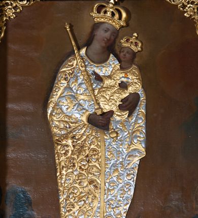 Zdjęcie nr 1: Obraz w formie stojącego prostokąta z przedstawieniem Matki Boskiej z Dzieciątkiem unoszącej się pomiędzy członkami bractwa i wiernymi. Maria ukazana jest w całej postaci, zwrócona frontalnie, z głową skierowaną w lewo, stoi na globie i na sierpie księżyca. Na lewym przedramieniu podtrzymuje Dzieciątko, w prawej dłoni trzyma berło. Maria ma pełną twarz, o okrągłych oczach i małym nosie, okoloną długimi, brązowymi włosami opadającymi wzdłuż ramion. W partii szat obraz przesłania płaskorzeźbiona sukienka, w postaci złoconej sukni o srebrzonym, akantowym wzorze oraz srebrzony płaszcz o złoconym, akantowym wzorze, narzucony na ramiona i podtrzymywany prawą ręką z przodu postaci. Maria ma na głowie płaskorzeźbioną koronę zamkniętą. Dzieciątko zwrócone jest w trzech czwartych w prawo, lewą ręką podtrzymuje jabłko królewskie, prawą błogosławi. Ma okrągłą twarz, o pełnych policzkach, okrągłych oczach skierowanych do góry, małym nosie i pełnych ustach, okoloną krótkimi, brązowymi włosami. W partii szat przesłonięte jest płaskorzeźbioną, złoconą sukienką o akantowym wzorze. Na głowie ma płaskorzeźbioną, zamkniętą koroną. Po prawej stronie Marii znajdują się dwie postacie członków bractwa w kapturach na głowach, z rękami złożonymi w geście modlitwy. Po lewej stronie Marii dwie postacie kobiece zwrócone w trzech czwartych, z rękami złożonymi w geście modlitwy. Postacie zostały ukazane na tle zachmurzonego brązowo-żółtego nieba, rozświetlonego wokół głowy Marii i Dzieciątka. W górnych narożach obraz dekorowany złoconym ornamentem rocaille&#039;owym z kwiatami. 