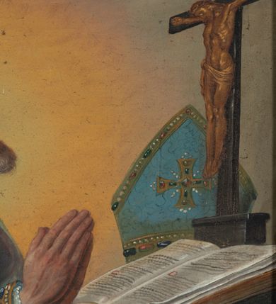 Zdjęcie nr 3: Obraz w formie stojącego prostokąta z przedstawieniem biskupa klęczącego przed stolikiem z krucyfiksem. Biskup zwrócony profilem w lewo, z uniesioną głową i dłońmi złożonymi w geście modlitwy. Twarz ma szczupłą, o starczych rysach, głęboko osadzonych oczach, skierowanych w górę, garbatym nosie i rozchylonych ustach z widocznymi zębami. Okolona jest siwą brodą i falowanymi włosami, na głowie ma łysinę. Ubrany jest w białą albę, niebieską, wzorzystą kapę, z dekoracyjną bordiurą z perłami i rautami, opadającą na ziemię. O jego prawe ramię oparty jest pastorał. Święty klęczy przed stołem nakrytym zieloną tkaniną, na nim leżą otwarta księga, krucyfiks i niebieska infuła. Obok stołu, na ziemi, zamknięta księga. Święty ukazany na szarym tle, rozświetlonym wokół jego postaci. 