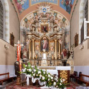 Zdjęcie nr 1: Nastawa architektoniczna, jednokondygnacyjna ze zwieńczeniem, jednoosiowa z bramkami. Ołtarz sarkofagowy z drewnianą mensą i portatylem. Na mensie znajduje się tabernakulum z tronem wystawienia. Tabernakulum w formie drewnianej skrzynki na planie wieloboku, ustawionej na cokole dekorowanym akantem, zamkniętej profilowaną listwą; ścianki dekorowane płycinami z akantem. Drzwiczki drewniane, obite blachą, w formie stojącego prostokąta, zdobione motywem krzyża, gorejącego serca, winnego grona i kłosów zboża. Tron wystawienia w formie obrotowej niszy, ujętej motywem winnego grona, flankowanej pilastrami dekorowanymi kampanulami, dźwigającymi gzyms zamykający całość, z wazonikami. Tron zwieńczony cokołem ze srebrzoną figurką leżącego baranka. 
Retabulum na dwustrefowym, uskokowym cokole ustawionym pod kątem, w górnej strefie z wyodrębnionymi po bokach postumentami i konsolami. Nastawa ujęta dwiema parami kolumn kompozytowych ustawionych na tle uskokowych, zwróconych pod kątem filarów, o trzonach dekorowanych płycinami z kampanulami. Podpory oraz dwa putta dźwigają wyłamane na ich osi, odcinkami wklęsło-wypukłe, pełne belkowanie, przerwane nad polem środkowym, z fryzem dekorowanym rozetami oraz fragmenty przerwanego, falistego przyczółka z siedzącymi na nim figurami aniołów. Na zewnętrznych krawędziach belkowania ustawione dwie figury w strojach żołnierzy. W polu środkowym nisza w formie stojącego prostokąta zamkniętego trójlistnie z uskokiem, o wklęsłych dolnych narożach, ujęta profilowaną ramą, z obrazem Trójcy Świętej i flankowana parą puttów. 
Zwieńczenie w formie stojącego prostokąta, flankowane parą zdwojonych pilastrów, zwróconych na zewnątrz, zamknięte odcinkiem gzymsu dekorowanym lambrekinem, ujęte obłokami z dwiema parami siedzących puttów. Powyżej medalion z okiem Opatrzności, ujętym obłokami i uskrzydlonymi główkami anielskimi, w glorii promienistej. W polu zwieńczenia obraz św. Jana Kantego w formie stojącego prostokąta, ujęty profilowaną ramą. 
Na wysokości cokołu nastawę flankują bramki utworzone przez postumenty przylegające do ścian prezbiterium zwieńczone fragmentami falistego przyczółka z latarniami. Cokoły przy ścianie z nastawą łączą listwy, tworząc przejścia, nad którymi stoją figury św. Piotra i św. Pawła. 
Struktura polichromowana w kolorze jasnozielonym, z brązowymi detalami, czerwonymi kapitelami; kolumny, ornamentyka i profile złocone, gloria i obłoki srebrzone. 

