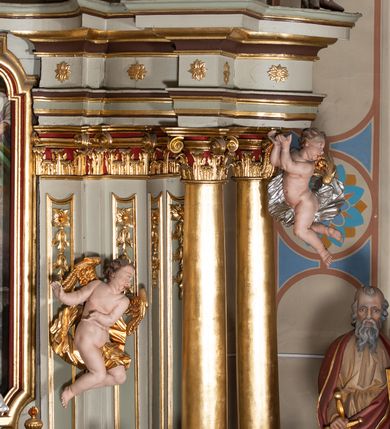 Zdjęcie nr 14: Nastawa architektoniczna, jednokondygnacyjna ze zwieńczeniem, jednoosiowa z bramkami. Ołtarz sarkofagowy z drewnianą mensą i portatylem. Na mensie znajduje się tabernakulum z tronem wystawienia. Tabernakulum w formie drewnianej skrzynki na planie wieloboku, ustawionej na cokole dekorowanym akantem, zamkniętej profilowaną listwą; ścianki dekorowane płycinami z akantem. Drzwiczki drewniane, obite blachą, w formie stojącego prostokąta, zdobione motywem krzyża, gorejącego serca, winnego grona i kłosów zboża. Tron wystawienia w formie obrotowej niszy, ujętej motywem winnego grona, flankowanej pilastrami dekorowanymi kampanulami, dźwigającymi gzyms zamykający całość, z wazonikami. Tron zwieńczony cokołem ze srebrzoną figurką leżącego baranka. 
Retabulum na dwustrefowym, uskokowym cokole ustawionym pod kątem, w górnej strefie z wyodrębnionymi po bokach postumentami i konsolami. Nastawa ujęta dwiema parami kolumn kompozytowych ustawionych na tle uskokowych, zwróconych pod kątem filarów, o trzonach dekorowanych płycinami z kampanulami. Podpory oraz dwa putta dźwigają wyłamane na ich osi, odcinkami wklęsło-wypukłe, pełne belkowanie, przerwane nad polem środkowym, z fryzem dekorowanym rozetami oraz fragmenty przerwanego, falistego przyczółka z siedzącymi na nim figurami aniołów. Na zewnętrznych krawędziach belkowania ustawione dwie figury w strojach żołnierzy. W polu środkowym nisza w formie stojącego prostokąta zamkniętego trójlistnie z uskokiem, o wklęsłych dolnych narożach, ujęta profilowaną ramą, z obrazem Trójcy Świętej i flankowana parą puttów. 
Zwieńczenie w formie stojącego prostokąta, flankowane parą zdwojonych pilastrów, zwróconych na zewnątrz, zamknięte odcinkiem gzymsu dekorowanym lambrekinem, ujęte obłokami z dwiema parami siedzących puttów. Powyżej medalion z okiem Opatrzności, ujętym obłokami i uskrzydlonymi główkami anielskimi, w glorii promienistej. W polu zwieńczenia obraz św. Jana Kantego w formie stojącego prostokąta, ujęty profilowaną ramą. 
Na wysokości cokołu nastawę flankują bramki utworzone przez postumenty przylegające do ścian prezbiterium zwieńczone fragmentami falistego przyczółka z latarniami. Cokoły przy ścianie z nastawą łączą listwy, tworząc przejścia, nad którymi stoją figury św. Piotra i św. Pawła. 
Struktura polichromowana w kolorze jasnozielonym, z brązowymi detalami, czerwonymi kapitelami; kolumny, ornamentyka i profile złocone, gloria i obłoki srebrzone. 

