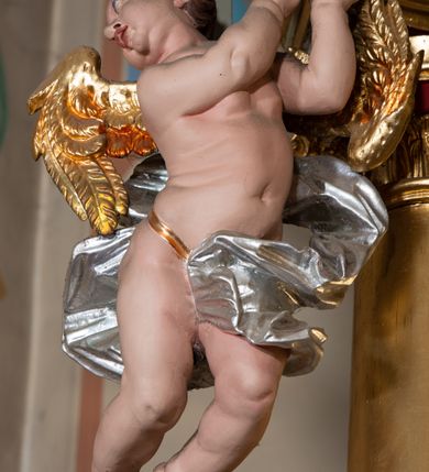 Zdjęcie nr 28: Nastawa architektoniczna, jednokondygnacyjna ze zwieńczeniem, jednoosiowa z bramkami. Ołtarz sarkofagowy z drewnianą mensą i portatylem. Na mensie znajduje się tabernakulum z tronem wystawienia. Tabernakulum w formie drewnianej skrzynki na planie wieloboku, ustawionej na cokole dekorowanym akantem, zamkniętej profilowaną listwą; ścianki dekorowane płycinami z akantem. Drzwiczki drewniane, obite blachą, w formie stojącego prostokąta, zdobione motywem krzyża, gorejącego serca, winnego grona i kłosów zboża. Tron wystawienia w formie obrotowej niszy, ujętej motywem winnego grona, flankowanej pilastrami dekorowanymi kampanulami, dźwigającymi gzyms zamykający całość, z wazonikami. Tron zwieńczony cokołem ze srebrzoną figurką leżącego baranka. 
Retabulum na dwustrefowym, uskokowym cokole ustawionym pod kątem, w górnej strefie z wyodrębnionymi po bokach postumentami i konsolami. Nastawa ujęta dwiema parami kolumn kompozytowych ustawionych na tle uskokowych, zwróconych pod kątem filarów, o trzonach dekorowanych płycinami z kampanulami. Podpory oraz dwa putta dźwigają wyłamane na ich osi, odcinkami wklęsło-wypukłe, pełne belkowanie, przerwane nad polem środkowym, z fryzem dekorowanym rozetami oraz fragmenty przerwanego, falistego przyczółka z siedzącymi na nim figurami aniołów. Na zewnętrznych krawędziach belkowania ustawione dwie figury w strojach żołnierzy. W polu środkowym nisza w formie stojącego prostokąta zamkniętego trójlistnie z uskokiem, o wklęsłych dolnych narożach, ujęta profilowaną ramą, z obrazem Trójcy Świętej i flankowana parą puttów. 
Zwieńczenie w formie stojącego prostokąta, flankowane parą zdwojonych pilastrów, zwróconych na zewnątrz, zamknięte odcinkiem gzymsu dekorowanym lambrekinem, ujęte obłokami z dwiema parami siedzących puttów. Powyżej medalion z okiem Opatrzności, ujętym obłokami i uskrzydlonymi główkami anielskimi, w glorii promienistej. W polu zwieńczenia obraz św. Jana Kantego w formie stojącego prostokąta, ujęty profilowaną ramą. 
Na wysokości cokołu nastawę flankują bramki utworzone przez postumenty przylegające do ścian prezbiterium zwieńczone fragmentami falistego przyczółka z latarniami. Cokoły przy ścianie z nastawą łączą listwy, tworząc przejścia, nad którymi stoją figury św. Piotra i św. Pawła. 
Struktura polichromowana w kolorze jasnozielonym, z brązowymi detalami, czerwonymi kapitelami; kolumny, ornamentyka i profile złocone, gloria i obłoki srebrzone. 

