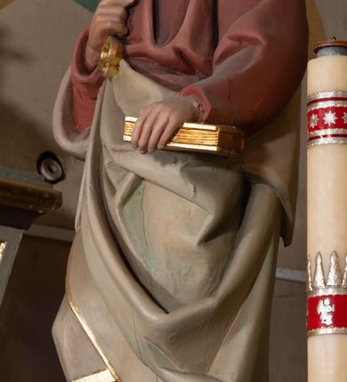 Zdjęcie nr 2: Rzeźba drążona z tyłu, ustawiona na podstawie na planie kwadratu o ściętych narożach. Święty ukazany jest w całej postaci, zwrócony frontalnie, z głową skierowaną w lewo, w kontrapoście. Lewą ręką trzyma przy boku księgę, prawą z kluczami w dłoni kładzie na piersi. Twarz ma pociągłą, o głęboko osadzonych oczach, uniesionych brwiach, dużym nosie i pełnych ustach, okoloną krótką, gęstą brodą oraz siwymi, krótkimi włosami z kosmykiem nad czołem. Ubrany jest w długą, czerwoną tunikę ze złoconą lamówką oraz osłaniający prawe ramię i zawinięty wokół postaci szary płaszcz ze złotą lamówką. Polichromia naturalistyczna w partiach ciała. 