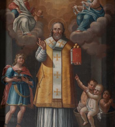 Zdjęcie nr 7: Obraz w formie stojącego prostokąta. W centrum przedstawienie św. Mikołaja z Jezusem i Marią unoszących się na obłokach w górnej części dzieła. Święty ukazany w całej postaci, frontalnie, lewą ręką podtrzymuje księgę z trzema kulami, prawą unosi z dłonią w geście błogosławieństwa. Twarz ma kwadratową z wysokim czołem, o starczych rysach, dużych oczach, prostym nosie i pełnych, rozchylonych ustach, okoloną siwą, kręcona brodą oraz siwymi, kręconymi włosami, sięgającymi ramion. Święty ubrany jest w strój biskupa wschodniego: biały sticharion, żółty sakkos z palicą przy boku oraz omoforion, na stopach ma buty. Po lewej stronie świętego znajduje się szaflik z trójką dzieci. Po jego prawej stronie postać młodzieńca, o pełnej, rumianej twarzy, okolonej jasnymi, kręconymi włosami, ubranego w niebieską tunikę sięgającą kolan oraz jasnoczerwony płaszcz zapięty na prawym ramieniu. Chłopiec trzyma tacę z karafką i dwoma kubkami. Postacie ukazane we wnętrzu. W górnej części obrazu centrycznie rozchodzące się, rozświetlone obłoki. W prawym górnym rogu siedząca na obłoku postać Chrystusa, skierowanego w trzech czwartych w lewo, który w lewej ręce trzyma księgę, a w prawej, opartej na globie, berło. Ubrany jest w czerwoną tunikę i biały płaszcz. Księgę podaje mu putto. W lewym górnym rogu siedząca na obłoku postać Marii, zwróconej w trzech czwartych w prawo, w obu wyciągniętych w przód dłoniach trzyma omoforion. Ubrana jest w jasnoróżową tunikę, przepasaną w talii, niebieski płaszcz i zielony welon. 
