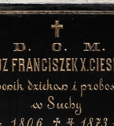 Zdjęcie nr 1: Tablica epitafijna wykonana z czarnego marmuru w kształcie leżącego prostokąta, z umieszczonym poniżej niewielkiego krzyża łacińskiego złoconym napisem „+ D(EO) O(PTIMO) M(AXIMO) / KSIĄDZ FRANCISZEK X(AWERY) CIESIELSKI / kanonik dziekan i proboszcz / w Suchy / * 1806. + 27/2 1873 r(oku)”, obwiedzionym cienką, złotą ramką. 