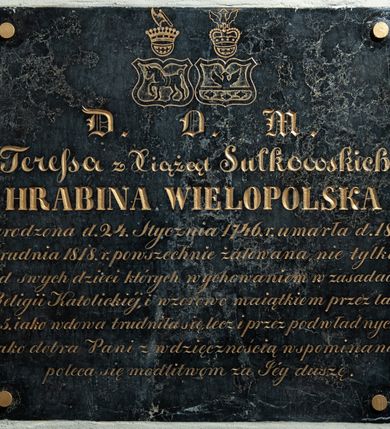 Zdjęcie nr 2: Tablica epitafijna w kształcie zbliżonym do kwadratu ze skomponowaną z różnej wielkości i typów  pisma inskrypcją poniżej herbów Starykoń i Sulima. Upamiętniający zmarłą napis został pozłocony. „D(EO) O(PTIMO) M(AXIMO) / Teresa z Xiążąt Sułkowskich / HRABINA WIELOPOLSKA / urodzona d(nia) 24. Stycznia 1746. r(oku) umarła d(nia) 18. / Grudnia 1818 r(oku) powszechnie żałowana nie tylko / od swych dzieci których wychowaniem w zasadach / Religii Katolickiej, i wzorowo maiątkiem przez lat / 45. iako wdowa trudniła się, lecz i przez podwładnych / iako dobra Pani z wdzięcznością wspominana / poleca się modliwtom ze Jey duszę”. 