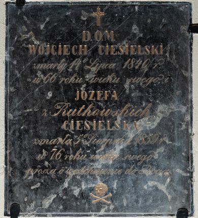 Zdjęcie nr 1: Tablica w kształcie stojącego prostokąta z wyrytym między niewielkim krzyżem łacińskim a czaszką powyżej skrzyżowanych piszczeli złoconym napisem „D(EO) O(PTIMO) M(AXIMO) / WOJCIECH CIESIELSKI / zmarły 14 Lipca 1840 r(oku) / w 66 roku wieku swego i / JÓZEFA / z Rutkowskich / CIESIELSKA / zmarła 5 Sierpnia 1859 r(oku) / w 76 roku wieku swego / proszą o westchnienie do Boga”. Pole napisu obwiedziono cienką, rytą ramką. 