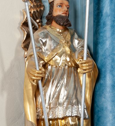 Zdjęcie nr 6: Rzeźba drążona, na cokole. Święty zwrócony frontalnie, w kontrapoście, o esowato wygiętej sylwetce. Obie ręce wyciąga przed siebie, w lewej trzyma włócznię, w prawej pastorał. Twarz ma pociągłą, o łagodnych rysach i z długą brodą, oczy głęboko osadzone, wydatny nos; włosy falowane, półdługie. Jest ubrany w złoconą albę, srebrzoną komżę z koronką przy brzegu, złoty mucet z guzikami oraz srebrzoną kapę zapiętą na piersi, ze złotą lamówką i podbiciem. Na głowie ma złoconą infułę. Polichromia naturalistyczna w odsłoniętych partiach ciała, szaty i atrybuty złocone i srebrzone.