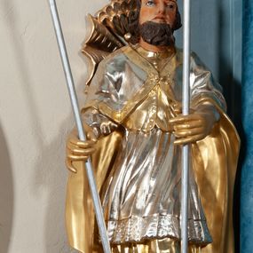 Zdjęcie nr 1: Rzeźba drążona, na cokole. Święty zwrócony frontalnie, w kontrapoście, o esowato wygiętej sylwetce. Obie ręce wyciąga przed siebie, w lewej trzyma włócznię, w prawej pastorał. Twarz ma pociągłą, o łagodnych rysach i z długą brodą, oczy głęboko osadzone, wydatny nos; włosy falowane, półdługie. Jest ubrany w złoconą albę, srebrzoną komżę z koronką przy brzegu, złoty mucet z guzikami oraz srebrzoną kapę zapiętą na piersi, ze złotą lamówką i podbiciem. Na głowie ma złoconą infułę. Polichromia naturalistyczna w odsłoniętych partiach ciała, szaty i atrybuty złocone i srebrzone.