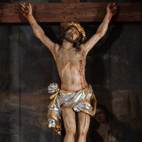 Zdjęcie nr 1: Pole główne ołtarza wypełnia figura Chrystusa Ukrzyżowanego na tle obrazu. Rzeźba pełna przedstawia żywego jeszcze Zbawiciela. Ciało oddano w dużym zwisie, o układzie ramion zbliżonym do litery „V” i esowato wygiętej sylwetce. Jezus ma nogi ugięte w kolanach, stopy przybite dwoma gwoździami, prawą nad lewą. Ciało szczupłe o wyraźnie podkreślonej muskulaturze i pracy mięśni, z zaznaczonymi śladami męki na lewym boku i w miejscach przebicia gwoździami. Głowa w grubej koronie cierniowej, przechylona na lewe ramię, uniesiona, ze wzrokiem skierowanym do góry. Twarz szczupła, okolona krótką brodą, nos długi, wąski, usta rozchylone. Włosy kręcone w pukle opadają na lewe ramię i plecy. Perizonium krótkie, utworzone ze skręconej, drapowanej i skrzyżowanej tkaniny, ze złoconą lamówką; przewiązane na prawym boku sznurem z chwostami, z obfitym, gęsto drapowanym zwisem sięgającym kolan. Polichromia naturalistyczna w partiach ciała; perizonium srebrzone i złocone, korona cierniowa i sznur złocone. W górnej części pionowej belki krzyża titulus w formie zwoju z napisem „IN/RI”. W tle, po prawej stronie krzyża postać klęczącej Marii Magdaleny, zwróconej w trzech czwartych w stronę Chrytsusa. Jej lewa ręka spoczywa na piersi, prawa ujmuje belkę krzyża. Ma pełną, młodzieńczą twarz, włosy długie, opadające na ramiona i plecy z wplecionymi sznurami pereł. Ubrana jest w białą suknię przewiązaną w talii oraz niebieski płaszcz połamany w grube fałdy na rękawach. U jej nóg puszka na wonności. W lewej dolnej części obrazu przedstawienie Jerozolimy wśród gór. Obraz w połowie przecina jaśniejsza linia horyzontu, powyżej widoczne ciemne niebo z kłębiastymi chmurami. Kolorystyka obrazu ciemna, kontrastująca z figurą Ukrzyżowanego. 