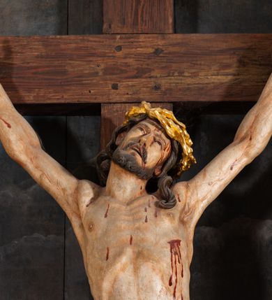 Zdjęcie nr 5: Pole główne ołtarza wypełnia figura Chrystusa Ukrzyżowanego na tle obrazu. Rzeźba pełna przedstawia żywego jeszcze Zbawiciela. Ciało oddano w dużym zwisie, o układzie ramion zbliżonym do litery „V” i esowato wygiętej sylwetce. Jezus ma nogi ugięte w kolanach, stopy przybite dwoma gwoździami, prawą nad lewą. Ciało szczupłe o wyraźnie podkreślonej muskulaturze i pracy mięśni, z zaznaczonymi śladami męki na lewym boku i w miejscach przebicia gwoździami. Głowa w grubej koronie cierniowej, przechylona na lewe ramię, uniesiona, ze wzrokiem skierowanym do góry. Twarz szczupła, okolona krótką brodą, nos długi, wąski, usta rozchylone. Włosy kręcone w pukle opadają na lewe ramię i plecy. Perizonium krótkie, utworzone ze skręconej, drapowanej i skrzyżowanej tkaniny, ze złoconą lamówką; przewiązane na prawym boku sznurem z chwostami, z obfitym, gęsto drapowanym zwisem sięgającym kolan. Polichromia naturalistyczna w partiach ciała; perizonium srebrzone i złocone, korona cierniowa i sznur złocone. W górnej części pionowej belki krzyża titulus w formie zwoju z napisem „IN/RI”. W tle, po prawej stronie krzyża postać klęczącej Marii Magdaleny, zwróconej w trzech czwartych w stronę Chrytsusa. Jej lewa ręka spoczywa na piersi, prawa ujmuje belkę krzyża. Ma pełną, młodzieńczą twarz, włosy długie, opadające na ramiona i plecy z wplecionymi sznurami pereł. Ubrana jest w białą suknię przewiązaną w talii oraz niebieski płaszcz połamany w grube fałdy na rękawach. U jej nóg puszka na wonności. W lewej dolnej części obrazu przedstawienie Jerozolimy wśród gór. Obraz w połowie przecina jaśniejsza linia horyzontu, powyżej widoczne ciemne niebo z kłębiastymi chmurami. Kolorystyka obrazu ciemna, kontrastująca z figurą Ukrzyżowanego. 