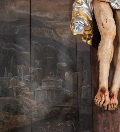 Zdjęcie nr 16: Pole główne ołtarza wypełnia figura Chrystusa Ukrzyżowanego na tle obrazu. Rzeźba pełna przedstawia żywego jeszcze Zbawiciela. Ciało oddano w dużym zwisie, o układzie ramion zbliżonym do litery „V” i esowato wygiętej sylwetce. Jezus ma nogi ugięte w kolanach, stopy przybite dwoma gwoździami, prawą nad lewą. Ciało szczupłe o wyraźnie podkreślonej muskulaturze i pracy mięśni, z zaznaczonymi śladami męki na lewym boku i w miejscach przebicia gwoździami. Głowa w grubej koronie cierniowej, przechylona na lewe ramię, uniesiona, ze wzrokiem skierowanym do góry. Twarz szczupła, okolona krótką brodą, nos długi, wąski, usta rozchylone. Włosy kręcone w pukle opadają na lewe ramię i plecy. Perizonium krótkie, utworzone ze skręconej, drapowanej i skrzyżowanej tkaniny, ze złoconą lamówką; przewiązane na prawym boku sznurem z chwostami, z obfitym, gęsto drapowanym zwisem sięgającym kolan. Polichromia naturalistyczna w partiach ciała; perizonium srebrzone i złocone, korona cierniowa i sznur złocone. W górnej części pionowej belki krzyża titulus w formie zwoju z napisem „IN/RI”. W tle, po prawej stronie krzyża postać klęczącej Marii Magdaleny, zwróconej w trzech czwartych w stronę Chrytsusa. Jej lewa ręka spoczywa na piersi, prawa ujmuje belkę krzyża. Ma pełną, młodzieńczą twarz, włosy długie, opadające na ramiona i plecy z wplecionymi sznurami pereł. Ubrana jest w białą suknię przewiązaną w talii oraz niebieski płaszcz połamany w grube fałdy na rękawach. U jej nóg puszka na wonności. W lewej dolnej części obrazu przedstawienie Jerozolimy wśród gór. Obraz w połowie przecina jaśniejsza linia horyzontu, powyżej widoczne ciemne niebo z kłębiastymi chmurami. Kolorystyka obrazu ciemna, kontrastująca z figurą Ukrzyżowanego. 