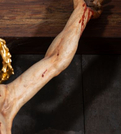 Zdjęcie nr 18: Pole główne ołtarza wypełnia figura Chrystusa Ukrzyżowanego na tle obrazu. Rzeźba pełna przedstawia żywego jeszcze Zbawiciela. Ciało oddano w dużym zwisie, o układzie ramion zbliżonym do litery „V” i esowato wygiętej sylwetce. Jezus ma nogi ugięte w kolanach, stopy przybite dwoma gwoździami, prawą nad lewą. Ciało szczupłe o wyraźnie podkreślonej muskulaturze i pracy mięśni, z zaznaczonymi śladami męki na lewym boku i w miejscach przebicia gwoździami. Głowa w grubej koronie cierniowej, przechylona na lewe ramię, uniesiona, ze wzrokiem skierowanym do góry. Twarz szczupła, okolona krótką brodą, nos długi, wąski, usta rozchylone. Włosy kręcone w pukle opadają na lewe ramię i plecy. Perizonium krótkie, utworzone ze skręconej, drapowanej i skrzyżowanej tkaniny, ze złoconą lamówką; przewiązane na prawym boku sznurem z chwostami, z obfitym, gęsto drapowanym zwisem sięgającym kolan. Polichromia naturalistyczna w partiach ciała; perizonium srebrzone i złocone, korona cierniowa i sznur złocone. W górnej części pionowej belki krzyża titulus w formie zwoju z napisem „IN/RI”. W tle, po prawej stronie krzyża postać klęczącej Marii Magdaleny, zwróconej w trzech czwartych w stronę Chrytsusa. Jej lewa ręka spoczywa na piersi, prawa ujmuje belkę krzyża. Ma pełną, młodzieńczą twarz, włosy długie, opadające na ramiona i plecy z wplecionymi sznurami pereł. Ubrana jest w białą suknię przewiązaną w talii oraz niebieski płaszcz połamany w grube fałdy na rękawach. U jej nóg puszka na wonności. W lewej dolnej części obrazu przedstawienie Jerozolimy wśród gór. Obraz w połowie przecina jaśniejsza linia horyzontu, powyżej widoczne ciemne niebo z kłębiastymi chmurami. Kolorystyka obrazu ciemna, kontrastująca z figurą Ukrzyżowanego. 