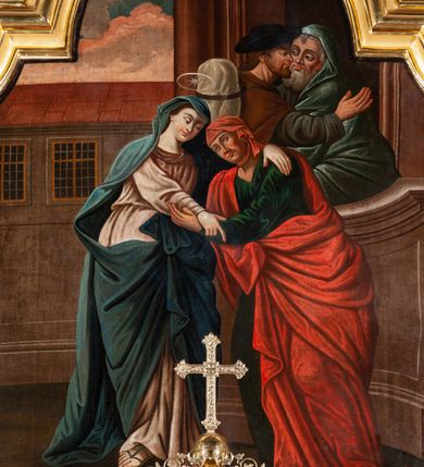 Zdjęcie nr 9: Obraz w formie stojącego prostokąta zamknięty łukiem półkolistym nadwieszonym z uskokami w złoconej, profilowanej ramie. W centrum postacie spotykających się Marii i św. Elżbiety. Kobiety zwrócone ku sobie obejmują się obiema rękami. Twarz Marii jest owalna o wyraźnych, młodzieńczych rysach, jasnej karnacji, nad głową nimb. Matka Boska jest ubrana w bladoróżową suknię przepasaną w talii oraz niebieski płaszcz nakrywający głowę i ramiona, przewiązany z przodu. Twarz św. Elżbiety jest owalna, zdradza jej starszy wiek, o ciemnej karnacji; oczy ma zwrócone w górę. Ubrana jest w zieloną suknię oraz czerwony płaszcz przerzucony przez prawe ramię i zawiązany na boku, na głowie ma jasnoczerwoną chustę. Na drugim planie w prawej części obrazu ukazany budynek, w którego wejściu przedstawione półpostacie witających się św. Józefa i Zachariasza. Scena została zakomponowana na tle architektury – na trzecim planie widoczny budynek z dwoma wielodzielnymi oknami. Powyżej w górnej części obrazu widoczny jest fragment błękitnego nieba z zabarwionymi na różowo obłokami. Kolorystyka ciemna, ciepła, postacie kobiet zostały wyróżnione intensywnym kolorem tkanin. Silny światłocień.