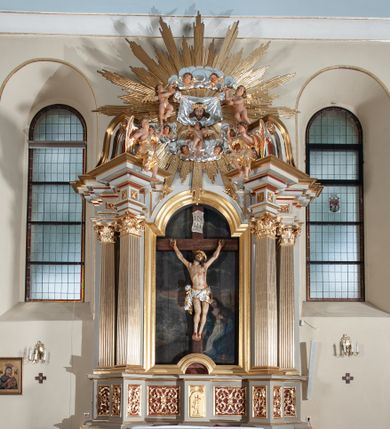 Zdjęcie nr 1: Nastawa ołtarzowa jednoosiowa, jednokondygnacyjna ze zwieńczeniem, na podwójnym cokole. Mensa ołtarzowa drewniana, prostopadłościenna. Antepedium w formie leżącego prostokąta w profilowanej ramie. Pole dekorowane rzeźbionym akantem o układzie symetrycznym względem osi środkowej, z elementami muszli oraz parą puttów po dwóch stronach centralnie ustawionej łodygi z kwiatem. Tabernakulum w formie prostopadłościanu zamkniętego gzymsem. Drzwiczki w kształcie stojącego prostokąta zamkniętego łukiem nadwieszonym w profilowanej ramie z płaskorzeźbionym przedstawieniem zmartwychwstałego Chrystusa; ujęte płyciną, dekorowaną w przyłuczach polami z akantem. Chrystus został ukazany w całej postaci, lewą ręka przytrzymując krzyż, prawą wskazuje ranę w boku. Przy jego prawej nodze stoi kielich. Pierwsza kondygnacja nastawy ujęta dwiema parami kolumn o kapitelach kompozytowych i kanelowanych trzonach o kwadratowym przekroju, ustawionych przed pilastrami; wewnętrzna para ustawiona skośnie względem lica ołtarza. Podpory dźwigają pełne belkowanie wyłamane na ich osi, przerwane nad polem środkowym; wewnętrzna para podtrzymuje imposty oraz przerwany, esowaty przyczółek z siedzącymi przed nim, na gzymsie, figurami aniołów w długich sukniach. Pole środkowe kondygnacji w formie stojącego prostokąta zamkniętego łukiem półkolistym nadwieszonym z wnęką z figurą Chrystusa Ukrzyżowanego na malowanym tle z Jerozolimą i postacią św. Marii Magdaleny. Zwieńczenie w formie bardzo rozbudowanej glorii promienistej, o naprzemiennie długich i krótkich wiązkach promieni; z płaskorzeźbionym mandylionem podtrzymywanym u spodu i po bokach przez trzy putta. Chustę św. Weroniki od góry i od dołu ujmują skłębione obłoki, między którymi widoczne główki anielskie. 
Oba cokoły dekorowane płycinami: w partii dolnego cokołu wypełnionymi ciemnoróżową marmoryzacją, w partii górnego ornamentem akantowym, mniejsze płyciny w partii fryzu. Struktura polichromowana na kolor jasnoszary, pola płycin i profilowania czerwone; kolumny, gloria, ornamentyka i profilowania złocone; chusta i obłoki srebrzone.
