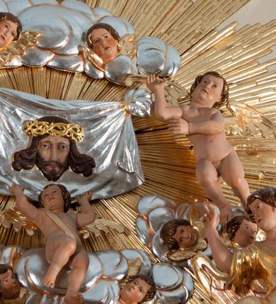 Zdjęcie nr 9: Nastawa ołtarzowa jednoosiowa, jednokondygnacyjna ze zwieńczeniem, na podwójnym cokole. Mensa ołtarzowa drewniana, prostopadłościenna. Antepedium w formie leżącego prostokąta w profilowanej ramie. Pole dekorowane rzeźbionym akantem o układzie symetrycznym względem osi środkowej, z elementami muszli oraz parą puttów po dwóch stronach centralnie ustawionej łodygi z kwiatem. Tabernakulum w formie prostopadłościanu zamkniętego gzymsem. Drzwiczki w kształcie stojącego prostokąta zamkniętego łukiem nadwieszonym w profilowanej ramie z płaskorzeźbionym przedstawieniem zmartwychwstałego Chrystusa; ujęte płyciną, dekorowaną w przyłuczach polami z akantem. Chrystus został ukazany w całej postaci, lewą ręka przytrzymując krzyż, prawą wskazuje ranę w boku. Przy jego prawej nodze stoi kielich. Pierwsza kondygnacja nastawy ujęta dwiema parami kolumn o kapitelach kompozytowych i kanelowanych trzonach o kwadratowym przekroju, ustawionych przed pilastrami; wewnętrzna para ustawiona skośnie względem lica ołtarza. Podpory dźwigają pełne belkowanie wyłamane na ich osi, przerwane nad polem środkowym; wewnętrzna para podtrzymuje imposty oraz przerwany, esowaty przyczółek z siedzącymi przed nim, na gzymsie, figurami aniołów w długich sukniach. Pole środkowe kondygnacji w formie stojącego prostokąta zamkniętego łukiem półkolistym nadwieszonym z wnęką z figurą Chrystusa Ukrzyżowanego na malowanym tle z Jerozolimą i postacią św. Marii Magdaleny. Zwieńczenie w formie bardzo rozbudowanej glorii promienistej, o naprzemiennie długich i krótkich wiązkach promieni; z płaskorzeźbionym mandylionem podtrzymywanym u spodu i po bokach przez trzy putta. Chustę św. Weroniki od góry i od dołu ujmują skłębione obłoki, między którymi widoczne główki anielskie. 
Oba cokoły dekorowane płycinami: w partii dolnego cokołu wypełnionymi ciemnoróżową marmoryzacją, w partii górnego ornamentem akantowym, mniejsze płyciny w partii fryzu. Struktura polichromowana na kolor jasnoszary, pola płycin i profilowania czerwone; kolumny, gloria, ornamentyka i profilowania złocone; chusta i obłoki srebrzone.
