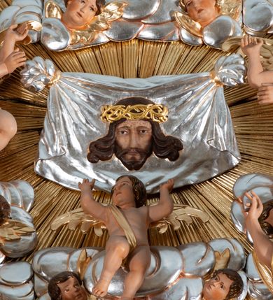 Zdjęcie nr 14: Nastawa ołtarzowa jednoosiowa, jednokondygnacyjna ze zwieńczeniem, na podwójnym cokole. Mensa ołtarzowa drewniana, prostopadłościenna. Antepedium w formie leżącego prostokąta w profilowanej ramie. Pole dekorowane rzeźbionym akantem o układzie symetrycznym względem osi środkowej, z elementami muszli oraz parą puttów po dwóch stronach centralnie ustawionej łodygi z kwiatem. Tabernakulum w formie prostopadłościanu zamkniętego gzymsem. Drzwiczki w kształcie stojącego prostokąta zamkniętego łukiem nadwieszonym w profilowanej ramie z płaskorzeźbionym przedstawieniem zmartwychwstałego Chrystusa; ujęte płyciną, dekorowaną w przyłuczach polami z akantem. Chrystus został ukazany w całej postaci, lewą ręka przytrzymując krzyż, prawą wskazuje ranę w boku. Przy jego prawej nodze stoi kielich. Pierwsza kondygnacja nastawy ujęta dwiema parami kolumn o kapitelach kompozytowych i kanelowanych trzonach o kwadratowym przekroju, ustawionych przed pilastrami; wewnętrzna para ustawiona skośnie względem lica ołtarza. Podpory dźwigają pełne belkowanie wyłamane na ich osi, przerwane nad polem środkowym; wewnętrzna para podtrzymuje imposty oraz przerwany, esowaty przyczółek z siedzącymi przed nim, na gzymsie, figurami aniołów w długich sukniach. Pole środkowe kondygnacji w formie stojącego prostokąta zamkniętego łukiem półkolistym nadwieszonym z wnęką z figurą Chrystusa Ukrzyżowanego na malowanym tle z Jerozolimą i postacią św. Marii Magdaleny. Zwieńczenie w formie bardzo rozbudowanej glorii promienistej, o naprzemiennie długich i krótkich wiązkach promieni; z płaskorzeźbionym mandylionem podtrzymywanym u spodu i po bokach przez trzy putta. Chustę św. Weroniki od góry i od dołu ujmują skłębione obłoki, między którymi widoczne główki anielskie. 
Oba cokoły dekorowane płycinami: w partii dolnego cokołu wypełnionymi ciemnoróżową marmoryzacją, w partii górnego ornamentem akantowym, mniejsze płyciny w partii fryzu. Struktura polichromowana na kolor jasnoszary, pola płycin i profilowania czerwone; kolumny, gloria, ornamentyka i profilowania złocone; chusta i obłoki srebrzone.
