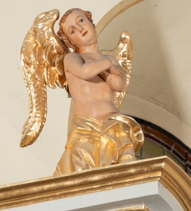 Zdjęcie nr 12: Nastawa ołtarzowa jednoosiowa, jednokondygnacyjna ze zwieńczeniem, na podwójnym cokole. Mensa drewniana, sarkofagowa. W polu antepedium stylizowane elementy rocaille’owe ujęte ornamentem roślinnym. Kondygnacja nastawy flankowana pilastrami oraz stojącą przed nimi parą kolumn o kapitelach kompozytowych. Cokoły kolumn profilowane, ustawione skośnie względem lica. Podpory dźwigają pełne belkowanie o wklęsłej linii, wyłamane na ich osiach, połączone nad polem środkowym gzymsem wygiętym w łuk oraz fragmenty przerwanego przyczółka z klęczącą parą adorujących aniołów. W polu środkowym obraz z przedstawieniem św. Michała Archanioła ujęty profilowaną ramą w formie stojącego prostokąta z dolną krawędzią wyniesioną w łuk i zamkniętego łukiem nadwieszonym z uskokiem. Na cokołach, obok kolumn, po lewej stronie wazon z kwiatami, po prawej święta niewiasta (św. Anna?). Kondygnacja ujęta ażurowymi uszami utworzonymi z rocaille’ów, kratki regencyjnej oraz rozwiniętych kwiatów. Zwieńczenie w formie zbliżonej do stojącego prostokąta o wklęsłych bokach zwężających się ku górze z uszakami, zamknięte falistym gzymsem. W polu obraz z przedstawieniem św. Hieronima w profilowanej ramie w formie stojącego prostokąta o wklęsłych bokach i dolnych narożach rozszerzającego się ku dołowi, zamkniętego łukiem nadwieszonym z uskokami. Cokoły nastawy dekorowane płycinami o fantazyjnym zarysie oraz w formie leżących prostokątów. Trzony pilastrów zdobione płycinami; wewnętrzna para wypełniona rocaille’em. Pole główne, zwieńczenie oraz uszaki dekorowane elementami rocaille’owymi. Zwieńczenie ujęte roślinnymi festonami. Struktura polichromowana na biało; cokoły, ołtarz i predella marmoryzowane w kolorze beżowym; kolumny, ornamentyka i profile złocone i srebrzone.