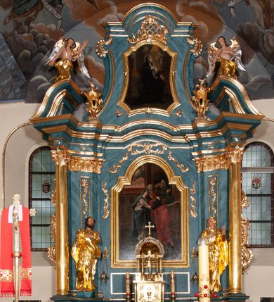 Zdjęcie nr 1: Nastawa ołtarzowa jednoosiowa, jednokondygnacyjna ze zwieńczeniem, na podwójnym cokole. Mensa drewniana, późniejsza, wklęsło-wypukła, dekorowana na krawędziach i ścianie frontowej motywami roślinnymi. Kondygnacja nastawy ujęta zwielokrotnionymi pilastrami o kapitelach kompozytowych ustawionymi skośnie oraz stojącą przed nimi parą kolumn o o takich samych kapitelach. Podpory dźwigają pełne belkowanie, o wklęsło-wypukłym zarysie, wyłamane na ich osi; nad polem środkowym przyjmujące formę łuku odcinkowego. Kolumny podtrzymują przerwany przyczółek, na którym klęczą figury aniołów. Podpory ustawione zostały na profilowanych cokołach. W polu środkowym obraz z przedstawieniem Nawiedzenia Najświętszej Marii Panny w profilowanej ramie w kształcie stojącego prostokąta zamkniętego łukiem nadwieszonym z uskokiem. Pole flankowane przez figury św. Anny z prawej strony i św. Joachima z lewej. Zwieńczenie w formie wydłużonego, stojącego prostokąta ujętego spływami wolutowymi, zamkniętego gzymsem w kształcie łuku nadwieszonego. W polu obraz z przedstawieniem św. Moniki w profilowanej ramie w kształcie stojącego prostokąta o wklęsłych bokach, zamkniętego łukiem nadwieszonym. Pod mensą rozeta z czterema palmetami. W partii cokołu płycina. Trzony pilastrów dekorowane płycinami z rocaille’m. Pole obrazowe flankuje rocaille, nad łukiem rozeta z liśćmi i rocaille. Kondygnacja ujęta uszami utworzonymi z ażurowego rocaille’a i kratką regencyjną. Na belkowaniu dwa rocaille’owe wazony. Woluty spływów zwieńczenia zdobione rocaille’m; ponad obrazem rocaille z kratką regencyjną. Struktura w całości marmoryzowana na niebiesko; kolumny, ornamentyka oraz profile złocone, skrzydła aniołów srebrzone.