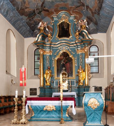 Zdjęcie nr 5: Nastawa ołtarzowa jednoosiowa, jednokondygnacyjna ze zwieńczeniem, na podwójnym cokole. Mensa drewniana, późniejsza, wklęsło-wypukła, dekorowana na krawędziach i ścianie frontowej motywami roślinnymi. Kondygnacja nastawy ujęta zwielokrotnionymi pilastrami o kapitelach kompozytowych ustawionymi skośnie oraz stojącą przed nimi parą kolumn o o takich samych kapitelach. Podpory dźwigają pełne belkowanie, o wklęsło-wypukłym zarysie, wyłamane na ich osi; nad polem środkowym przyjmujące formę łuku odcinkowego. Kolumny podtrzymują przerwany przyczółek, na którym klęczą figury aniołów. Podpory ustawione zostały na profilowanych cokołach. W polu środkowym obraz z przedstawieniem Nawiedzenia Najświętszej Marii Panny w profilowanej ramie w kształcie stojącego prostokąta zamkniętego łukiem nadwieszonym z uskokiem. Pole flankowane przez figury św. Anny z prawej strony i św. Joachima z lewej. Zwieńczenie w formie wydłużonego, stojącego prostokąta ujętego spływami wolutowymi, zamkniętego gzymsem w kształcie łuku nadwieszonego. W polu obraz z przedstawieniem św. Moniki w profilowanej ramie w kształcie stojącego prostokąta o wklęsłych bokach, zamkniętego łukiem nadwieszonym. Pod mensą rozeta z czterema palmetami. W partii cokołu płycina. Trzony pilastrów dekorowane płycinami z rocaille’m. Pole obrazowe flankuje rocaille, nad łukiem rozeta z liśćmi i rocaille. Kondygnacja ujęta uszami utworzonymi z ażurowego rocaille’a i kratką regencyjną. Na belkowaniu dwa rocaille’owe wazony. Woluty spływów zwieńczenia zdobione rocaille’m; ponad obrazem rocaille z kratką regencyjną. Struktura w całości marmoryzowana na niebiesko; kolumny, ornamentyka oraz profile złocone, skrzydła aniołów srebrzone.