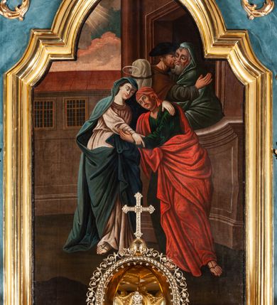 Zdjęcie nr 7: Nastawa ołtarzowa jednoosiowa, jednokondygnacyjna ze zwieńczeniem, na podwójnym cokole. Mensa drewniana, późniejsza, wklęsło-wypukła, dekorowana na krawędziach i ścianie frontowej motywami roślinnymi. Kondygnacja nastawy ujęta zwielokrotnionymi pilastrami o kapitelach kompozytowych ustawionymi skośnie oraz stojącą przed nimi parą kolumn o o takich samych kapitelach. Podpory dźwigają pełne belkowanie, o wklęsło-wypukłym zarysie, wyłamane na ich osi; nad polem środkowym przyjmujące formę łuku odcinkowego. Kolumny podtrzymują przerwany przyczółek, na którym klęczą figury aniołów. Podpory ustawione zostały na profilowanych cokołach. W polu środkowym obraz z przedstawieniem Nawiedzenia Najświętszej Marii Panny w profilowanej ramie w kształcie stojącego prostokąta zamkniętego łukiem nadwieszonym z uskokiem. Pole flankowane przez figury św. Anny z prawej strony i św. Joachima z lewej. Zwieńczenie w formie wydłużonego, stojącego prostokąta ujętego spływami wolutowymi, zamkniętego gzymsem w kształcie łuku nadwieszonego. W polu obraz z przedstawieniem św. Moniki w profilowanej ramie w kształcie stojącego prostokąta o wklęsłych bokach, zamkniętego łukiem nadwieszonym. Pod mensą rozeta z czterema palmetami. W partii cokołu płycina. Trzony pilastrów dekorowane płycinami z rocaille’m. Pole obrazowe flankuje rocaille, nad łukiem rozeta z liśćmi i rocaille. Kondygnacja ujęta uszami utworzonymi z ażurowego rocaille’a i kratką regencyjną. Na belkowaniu dwa rocaille’owe wazony. Woluty spływów zwieńczenia zdobione rocaille’m; ponad obrazem rocaille z kratką regencyjną. Struktura w całości marmoryzowana na niebiesko; kolumny, ornamentyka oraz profile złocone, skrzydła aniołów srebrzone.