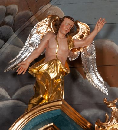 Zdjęcie nr 29: Nastawa ołtarzowa jednoosiowa, jednokondygnacyjna ze zwieńczeniem, na podwójnym cokole. Mensa drewniana, późniejsza, wklęsło-wypukła, dekorowana na krawędziach i ścianie frontowej motywami roślinnymi. Kondygnacja nastawy ujęta zwielokrotnionymi pilastrami o kapitelach kompozytowych ustawionymi skośnie oraz stojącą przed nimi parą kolumn o o takich samych kapitelach. Podpory dźwigają pełne belkowanie, o wklęsło-wypukłym zarysie, wyłamane na ich osi; nad polem środkowym przyjmujące formę łuku odcinkowego. Kolumny podtrzymują przerwany przyczółek, na którym klęczą figury aniołów. Podpory ustawione zostały na profilowanych cokołach. W polu środkowym obraz z przedstawieniem Nawiedzenia Najświętszej Marii Panny w profilowanej ramie w kształcie stojącego prostokąta zamkniętego łukiem nadwieszonym z uskokiem. Pole flankowane przez figury św. Anny z prawej strony i św. Joachima z lewej. Zwieńczenie w formie wydłużonego, stojącego prostokąta ujętego spływami wolutowymi, zamkniętego gzymsem w kształcie łuku nadwieszonego. W polu obraz z przedstawieniem św. Moniki w profilowanej ramie w kształcie stojącego prostokąta o wklęsłych bokach, zamkniętego łukiem nadwieszonym. Pod mensą rozeta z czterema palmetami. W partii cokołu płycina. Trzony pilastrów dekorowane płycinami z rocaille’m. Pole obrazowe flankuje rocaille, nad łukiem rozeta z liśćmi i rocaille. Kondygnacja ujęta uszami utworzonymi z ażurowego rocaille’a i kratką regencyjną. Na belkowaniu dwa rocaille’owe wazony. Woluty spływów zwieńczenia zdobione rocaille’m; ponad obrazem rocaille z kratką regencyjną. Struktura w całości marmoryzowana na niebiesko; kolumny, ornamentyka oraz profile złocone, skrzydła aniołów srebrzone.