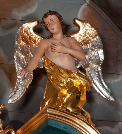 Zdjęcie nr 27: Nastawa ołtarzowa jednoosiowa, jednokondygnacyjna ze zwieńczeniem, na podwójnym cokole. Mensa drewniana, późniejsza, wklęsło-wypukła, dekorowana na krawędziach i ścianie frontowej motywami roślinnymi. Kondygnacja nastawy ujęta zwielokrotnionymi pilastrami o kapitelach kompozytowych ustawionymi skośnie oraz stojącą przed nimi parą kolumn o o takich samych kapitelach. Podpory dźwigają pełne belkowanie, o wklęsło-wypukłym zarysie, wyłamane na ich osi; nad polem środkowym przyjmujące formę łuku odcinkowego. Kolumny podtrzymują przerwany przyczółek, na którym klęczą figury aniołów. Podpory ustawione zostały na profilowanych cokołach. W polu środkowym obraz z przedstawieniem Nawiedzenia Najświętszej Marii Panny w profilowanej ramie w kształcie stojącego prostokąta zamkniętego łukiem nadwieszonym z uskokiem. Pole flankowane przez figury św. Anny z prawej strony i św. Joachima z lewej. Zwieńczenie w formie wydłużonego, stojącego prostokąta ujętego spływami wolutowymi, zamkniętego gzymsem w kształcie łuku nadwieszonego. W polu obraz z przedstawieniem św. Moniki w profilowanej ramie w kształcie stojącego prostokąta o wklęsłych bokach, zamkniętego łukiem nadwieszonym. Pod mensą rozeta z czterema palmetami. W partii cokołu płycina. Trzony pilastrów dekorowane płycinami z rocaille’m. Pole obrazowe flankuje rocaille, nad łukiem rozeta z liśćmi i rocaille. Kondygnacja ujęta uszami utworzonymi z ażurowego rocaille’a i kratką regencyjną. Na belkowaniu dwa rocaille’owe wazony. Woluty spływów zwieńczenia zdobione rocaille’m; ponad obrazem rocaille z kratką regencyjną. Struktura w całości marmoryzowana na niebiesko; kolumny, ornamentyka oraz profile złocone, skrzydła aniołów srebrzone.