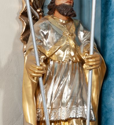 Zdjęcie nr 16: Nastawa ołtarzowa jednoosiowa, jednokondygnacyjna ze zwieńczeniem, na podwójnym cokole. Mensa drewniana, prostopadłościenna. Antepedium w formie leżącego prostokąta ujęte profilowaną ramą. W polu płaskorzeźbiona półpostać św. Augustyna ujętego u spodu płatkami kwiatu, flankowana banderolami. W prawej, uniesionej ręce trzyma księgę, lewą, ugiętą przytrzymuje pastorał, dłonią przyciska do piersi gorejące serce. Święty ukazany został jako starzec. Twarz ma pociągłą, okoloną krótką brodą, włosy sięgające szyi. Ubrany jest w niebieską tunikę i przerzucony przez ramiona płaszcz ze złoconą lamówką. Pole wypełnione jest płaskorzeźbionymi łodygami z kwiatami. Kondygnacja nastawy o wklęsłym licu, ujęta parą zwielokrotnionych pilastrów oraz stojącą przed nimi parą kolumn o kapitelach kompozytowych. Podpory dźwigają pełne belkowanie o silnie wysuniętym gzymsie, wyłamane na ich osi oraz przerwany przyczółek na linii kolumn. Po zewnętrznej stronie kolumn figury św. Wojciecha po lewej i św. Stanisława po prawej. W polu środkowym nisza w formie stojącego prostokąta otoczona profilowaną ramą; wewnątrz mniejszy obraz z przedstawieniem św. Jana Chrzciciela w profilowanym obramieniu w kształcie stojącego prostokąta. Zwieńczenie w kształcie stojącego prostokąta ujętego spływami wolutowymi, zamknięte gzymsem utworzonym ze zwróconych do siebie wolut; zakończone glorią promienistą z okrągłym polem z napisem „IHS” w otoczeniu obłoków. W polu zwieńczenia obraz z przedstawieniem św. Grzegorza w profilowanej ramie w formie stojącego prostokąta o wklęsłych bokach i narożach, zamkniętej łukiem nadwieszonym. Kondygnacja ujęta ażurowymi uszami utworzonymi z motywów roślinnych i karbowanej wstęgi. W partii belkowania nad polem środkowym rocaille&#039;owy kartusz. Nad obrazem w zwieńczeniu muszla i kampanule; woluty dekorowane festonami. Struktura polichromowana na kolor jasnoniebieski; trzony kolumn, antepedium i profile na niebiesko; ornamentyka i profile złocone.