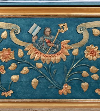 Zdjęcie nr 3: Nastawa ołtarzowa jednoosiowa, jednokondygnacyjna ze zwieńczeniem, na podwójnym cokole. Mensa drewniana, prostopadłościenna. Antepedium w formie leżącego prostokąta ujęte profilowaną ramą. W polu płaskorzeźbiona półpostać św. Augustyna ujętego u spodu płatkami kwiatu, flankowana banderolami. W prawej, uniesionej ręce trzyma księgę, lewą, ugiętą przytrzymuje pastorał, dłonią przyciska do piersi gorejące serce. Święty ukazany został jako starzec. Twarz ma pociągłą, okoloną krótką brodą, włosy sięgające szyi. Ubrany jest w niebieską tunikę i przerzucony przez ramiona płaszcz ze złoconą lamówką. Pole wypełnione jest płaskorzeźbionymi łodygami z kwiatami. Kondygnacja nastawy o wklęsłym licu, ujęta parą zwielokrotnionych pilastrów oraz stojącą przed nimi parą kolumn o kapitelach kompozytowych. Podpory dźwigają pełne belkowanie o silnie wysuniętym gzymsie, wyłamane na ich osi oraz przerwany przyczółek na linii kolumn. Po zewnętrznej stronie kolumn figury św. Wojciecha po lewej i św. Stanisława po prawej. W polu środkowym nisza w formie stojącego prostokąta otoczona profilowaną ramą; wewnątrz mniejszy obraz z przedstawieniem św. Jana Chrzciciela w profilowanym obramieniu w kształcie stojącego prostokąta. Zwieńczenie w kształcie stojącego prostokąta ujętego spływami wolutowymi, zamknięte gzymsem utworzonym ze zwróconych do siebie wolut; zakończone glorią promienistą z okrągłym polem z napisem „IHS” w otoczeniu obłoków. W polu zwieńczenia obraz z przedstawieniem św. Grzegorza w profilowanej ramie w formie stojącego prostokąta o wklęsłych bokach i narożach, zamkniętej łukiem nadwieszonym. Kondygnacja ujęta ażurowymi uszami utworzonymi z motywów roślinnych i karbowanej wstęgi. W partii belkowania nad polem środkowym rocaille&#039;owy kartusz. Nad obrazem w zwieńczeniu muszla i kampanule; woluty dekorowane festonami. Struktura polichromowana na kolor jasnoniebieski; trzony kolumn, antepedium i profile na niebiesko; ornamentyka i profile złocone.