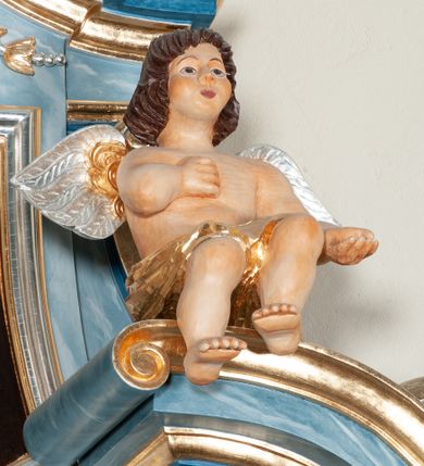 Zdjęcie nr 9: Nastawa ołtarzowa jednoosiowa, jednokondygnacyjna ze zwieńczeniem, na podwójnym cokole. Mensa drewniana, prostopadłościenna. Antepedium w formie leżącego prostokąta ujęte profilowaną ramą. W polu płaskorzeźbiona półpostać św. Augustyna ujętego u spodu płatkami kwiatu, flankowana banderolami. W prawej, uniesionej ręce trzyma księgę, lewą, ugiętą przytrzymuje pastorał, dłonią przyciska do piersi gorejące serce. Święty ukazany został jako starzec. Twarz ma pociągłą, okoloną krótką brodą, włosy sięgające szyi. Ubrany jest w niebieską tunikę i przerzucony przez ramiona płaszcz ze złoconą lamówką. Pole wypełnione jest płaskorzeźbionymi łodygami z kwiatami. Kondygnacja nastawy o wklęsłym licu, ujęta parą zwielokrotnionych pilastrów oraz stojącą przed nimi parą kolumn o kapitelach kompozytowych. Podpory dźwigają pełne belkowanie o silnie wysuniętym gzymsie, wyłamane na ich osi oraz przerwany przyczółek na linii kolumn. Po zewnętrznej stronie kolumn figury św. Wojciecha po lewej i św. Stanisława po prawej. W polu środkowym nisza w formie stojącego prostokąta otoczona profilowaną ramą; wewnątrz mniejszy obraz z przedstawieniem św. Jana Chrzciciela w profilowanym obramieniu w kształcie stojącego prostokąta. Zwieńczenie w kształcie stojącego prostokąta ujętego spływami wolutowymi, zamknięte gzymsem utworzonym ze zwróconych do siebie wolut; zakończone glorią promienistą z okrągłym polem z napisem „IHS” w otoczeniu obłoków. W polu zwieńczenia obraz z przedstawieniem św. Grzegorza w profilowanej ramie w formie stojącego prostokąta o wklęsłych bokach i narożach, zamkniętej łukiem nadwieszonym. Kondygnacja ujęta ażurowymi uszami utworzonymi z motywów roślinnych i karbowanej wstęgi. W partii belkowania nad polem środkowym rocaille&#039;owy kartusz. Nad obrazem w zwieńczeniu muszla i kampanule; woluty dekorowane festonami. Struktura polichromowana na kolor jasnoniebieski; trzony kolumn, antepedium i profile na niebiesko; ornamentyka i profile złocone.