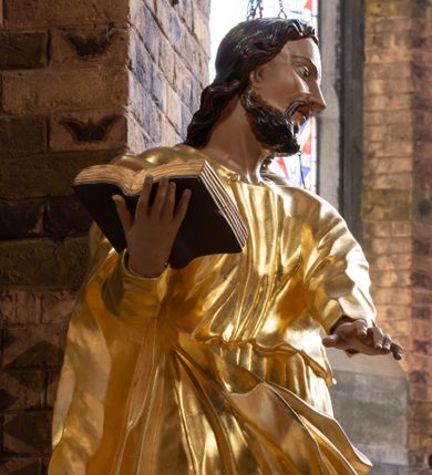 Zdjęcie nr 1: Rzeźba drążona na cokole z przedstawieniem św. Łukasza w całej postaci. Figura w kontrapoście, w skręcie w prawo, z głową zwróconą w lewo; w prawej wyciągniętej w bok ręce trzyma księgę, lewą unosi równolegle. Głowę ma lekko pochyloną; twarz szczupłą z wysokim czołem, o szeroko otwartych, ciemnych oczach, wąskim nosie i rozchylonych ustach. Twarz jest okolona krótkim kręconym zarostem oraz włosami układającymi się w spływające na kark fale. Święty jest ubrany w długą, przylegającą do ciała tunikę oraz płaszcz przewiązany diagonalnie z prawego ramienia przez plecy i wokół lewego biodra, złapany z przodu. Polichromia naturalistyczna w odsłoniętych partiach ciała, szaty złocone, księga brązowo-złota. Z uwagi na swoje aktualne ustawienie na ołtarzu głównym wydrążenie zostało zasłonięte zamalowanym na złoto materiałem.