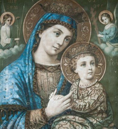 Zdjęcie nr 1: Obraz w kształcie zbliżonym do kwadratu w drewnianej, rzeźbionej w kimation ramie. W centrum ukazana w półpostaci Matka Boska z Dzieciątkiem na lewym ramieniu. Maria ma głowę przechyloną na lewe ramię, w prawej ręce trzyma rękę Dzieciątka. Ma owalną twarz o łagodnym wyrazie, niebieskie oczy, prosty nos i wąskie usta. Jest ubrana w jasnobrązową suknię z ciemniejszą lamówką i niebieski maforion. Dzieciątko siedzi, dłońmi dotyka ręki matki, głowę zwraca w lewo. Jest ubrane w długą, jasną tunikę. Stroje postaci są dekorowane aplikowaną tasiemką, postacie mają na głowach otwarte korony, a wokół głów nimby wypełnione stylizowaną wicią roślinną.  Po obu stronach głowy Marii ukazano anioły trzymające arma Christi. Anioł z lewej jest ubrany w białą suknię i zielony płaszcz, trzyma gąbkę na drzewcu oraz włócznię, a anioł z prawej jest ubrany w niebieską suknię z białymi dodatkami i trzyma krzyż papieski z trzema belkami.  W tle, powyżej aniołów napisy: po lewej stronie „MP” i „ΟΡМ”, a po prawej „ΘΥ” oraz „OΡГ”. Poniżej anioła po prawej stronie „IC-XC”. Tło jednolite, ciemnozielone.